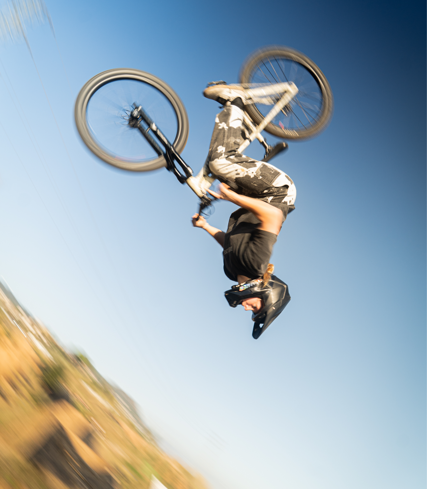 Person performing a bicycle trick against a clear blue sky