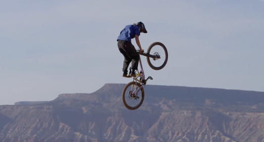 Lucy doing a seat stand trick on her mountain bike in the Utah desert
