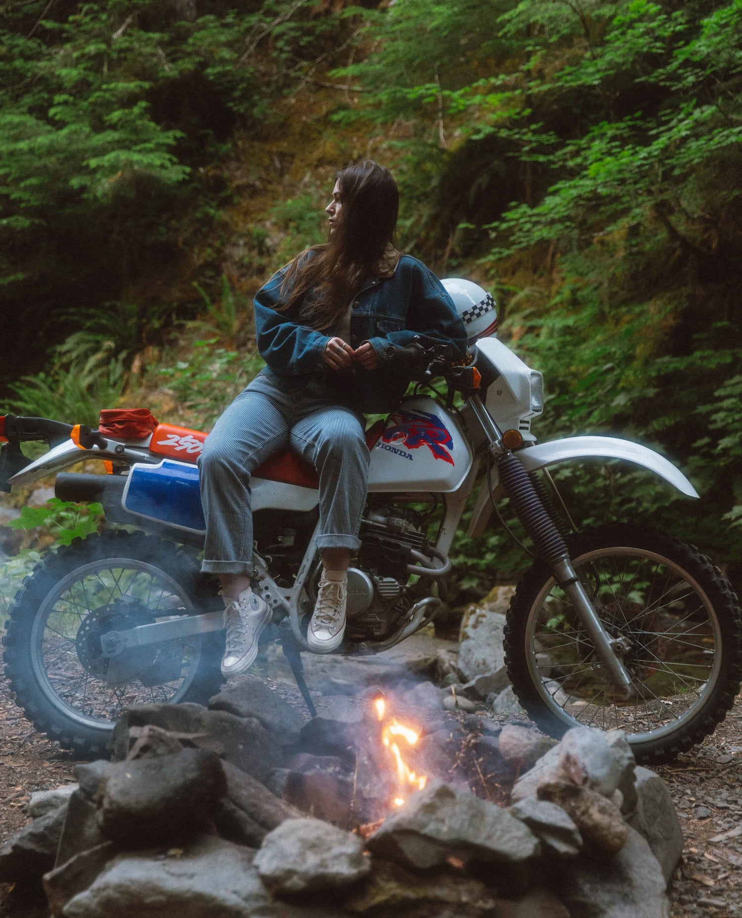 Alex sitting on her dirt bike by a campfire