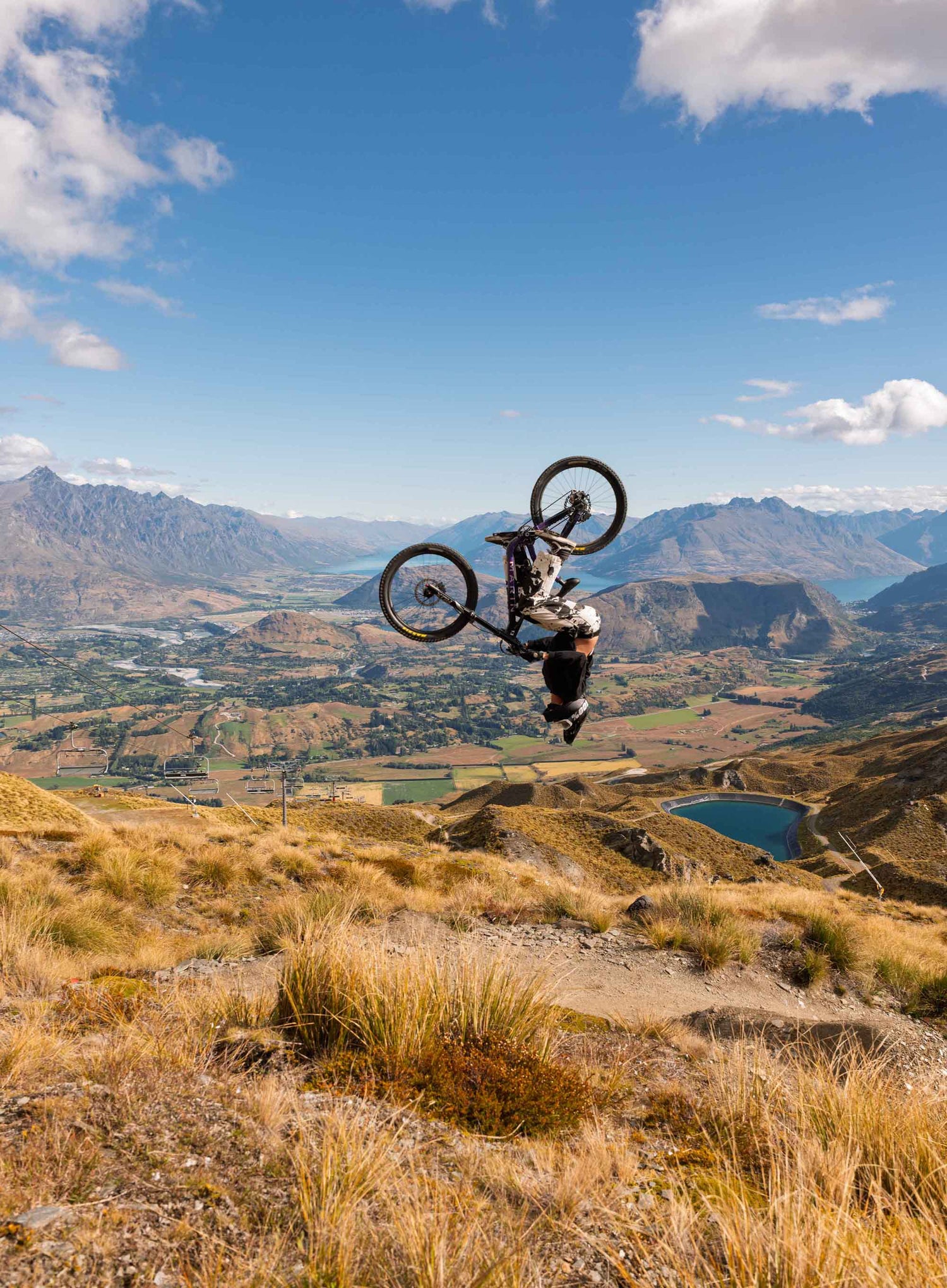 Person on a mountain bike performing a jump with mountains and sky in the background