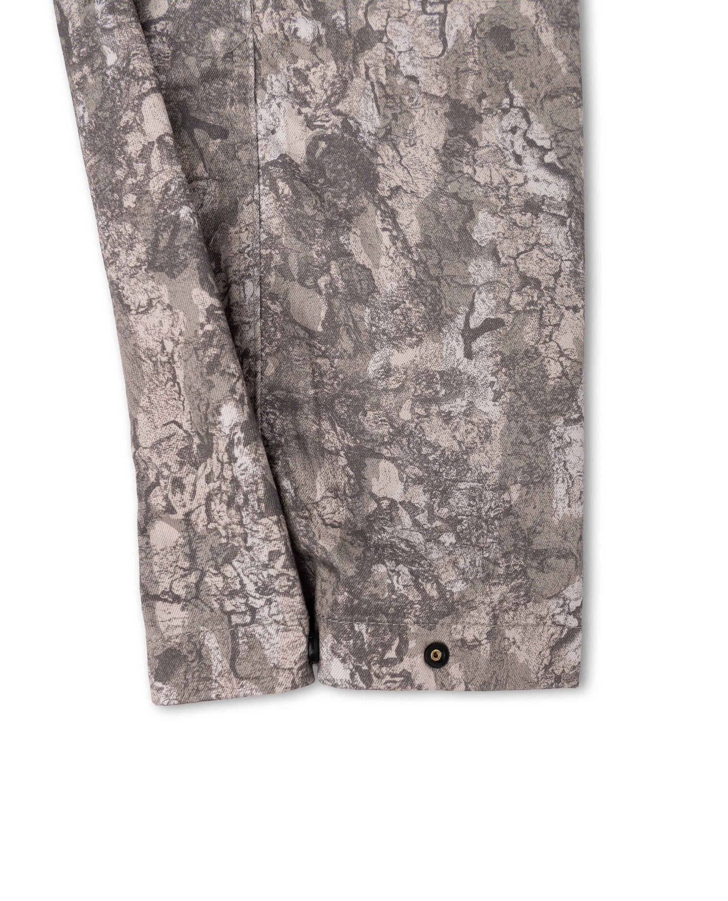 Close-up of a gray and beige camouflage-patterned fabric sleeve with a single dark button at the cuff, shown against a plain white background.