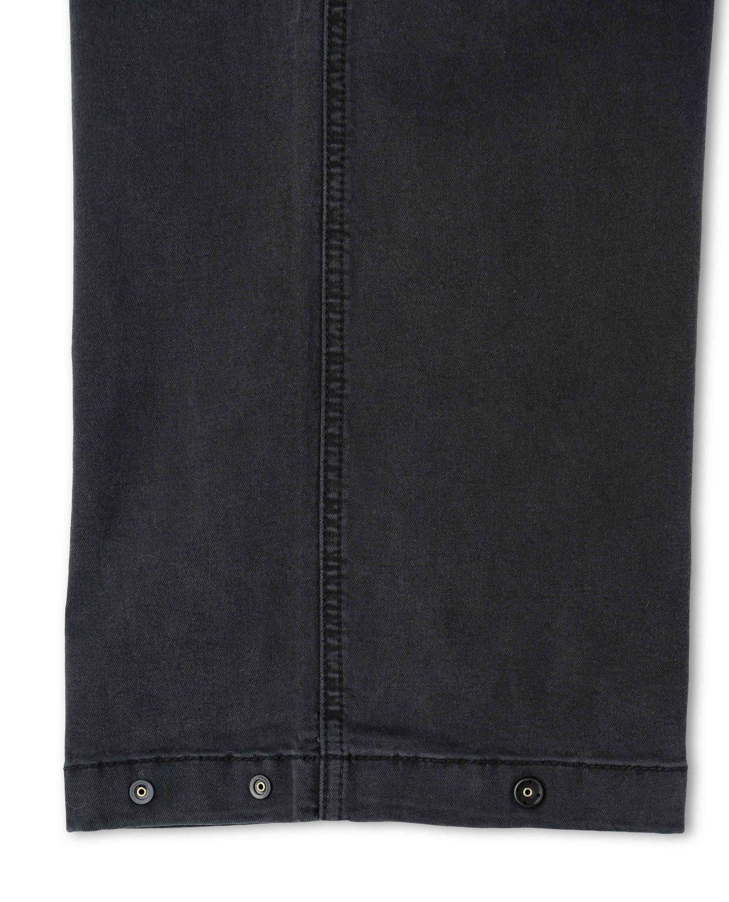 Close-up of a black denim jacket with button details on a white background