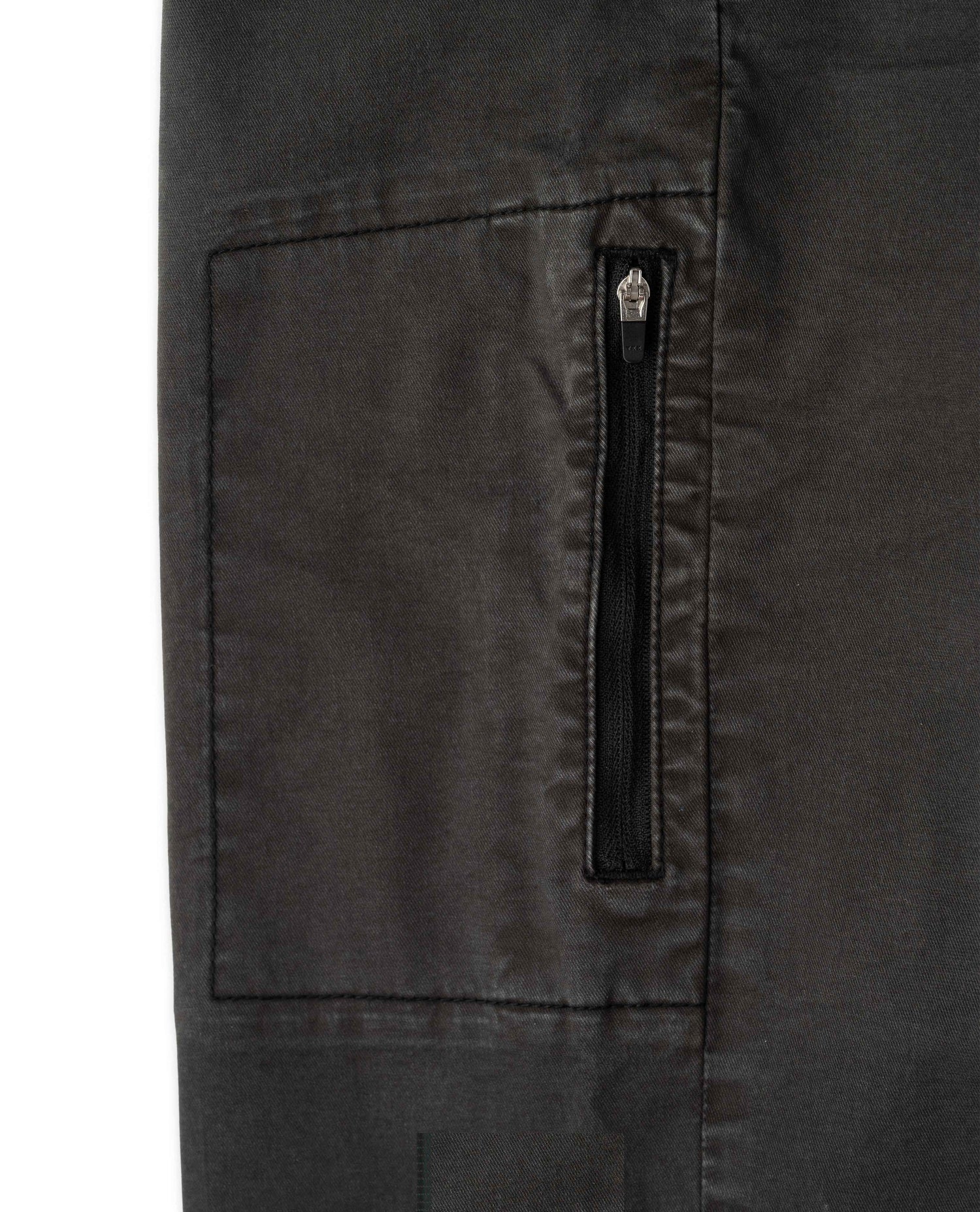 Close-up of a dark charcoal gray fabric garment showing a vertical zippered pocket with a silver zipper pull on a white background.