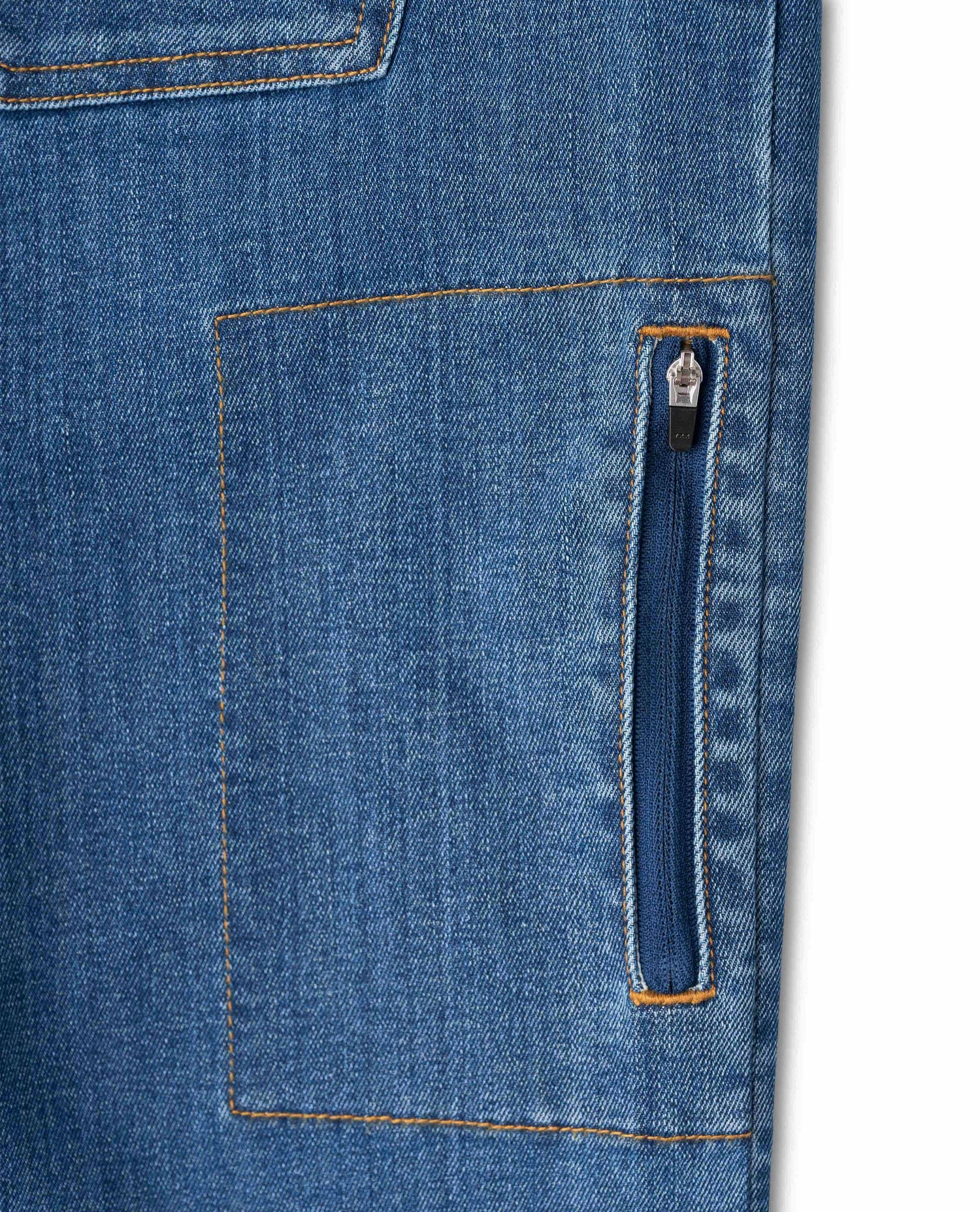 Zippered side pocket on medium wash blue jeans, with white background. 