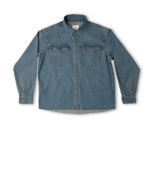 A medium-wash blue denim long-sleeve button-up shirt with two chest flap pockets, laid flat against a white background.