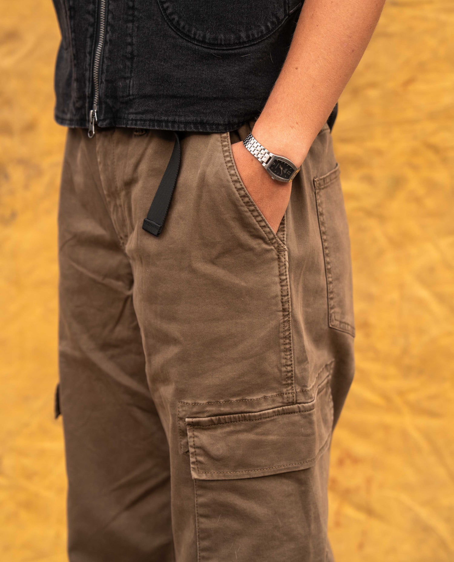 Close up of a brown pant with the model putting her hand in the pocket.