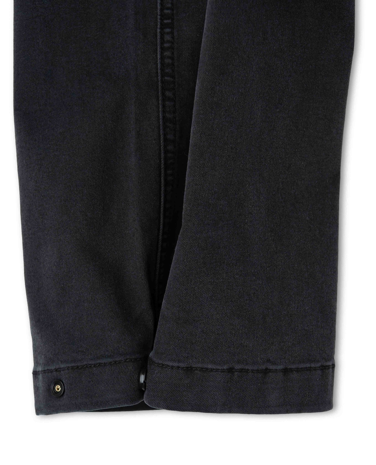 Close-up of black pants with a button on a white background