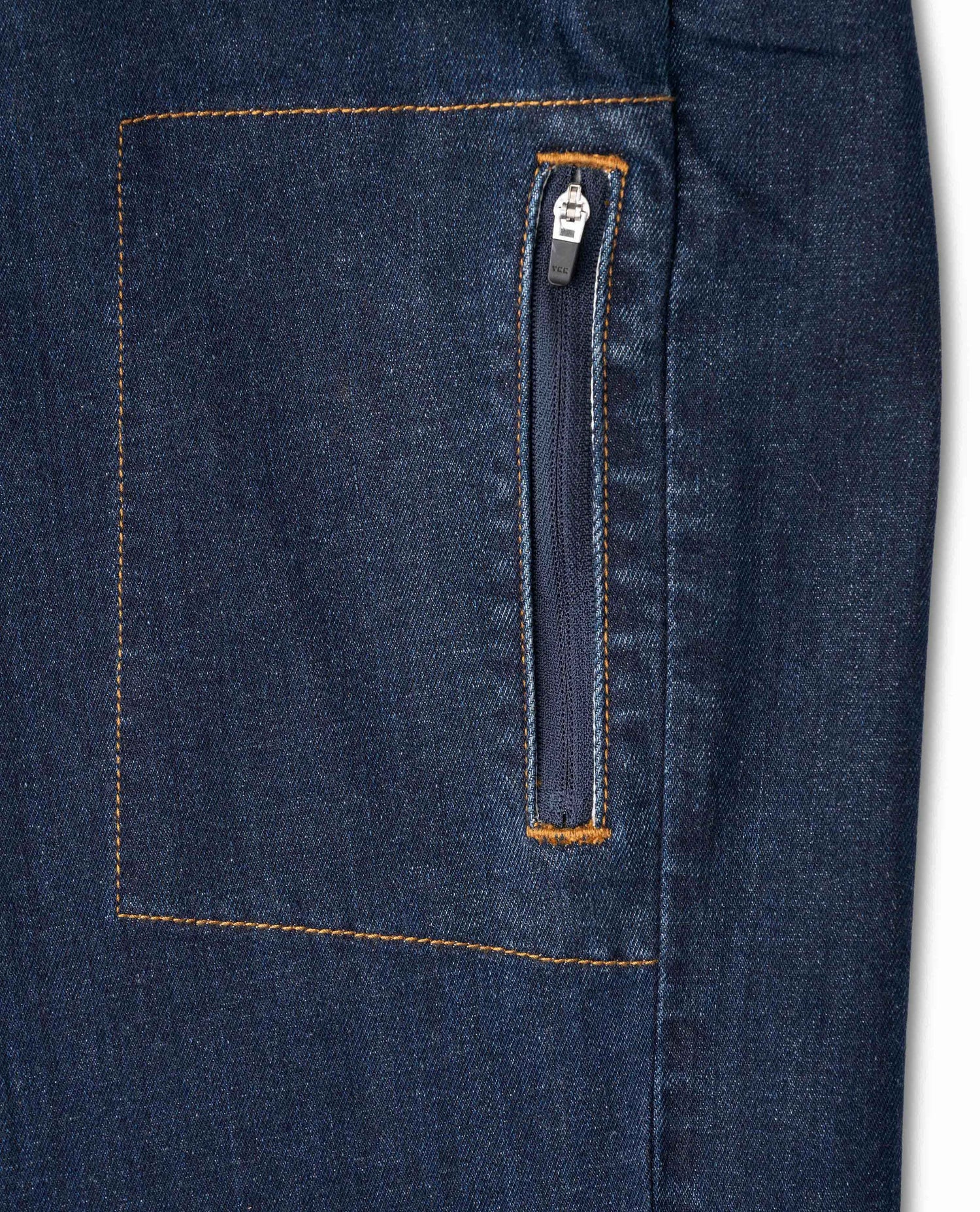 Detail shot of zippered pocket on side of dark wash jean with a white background
