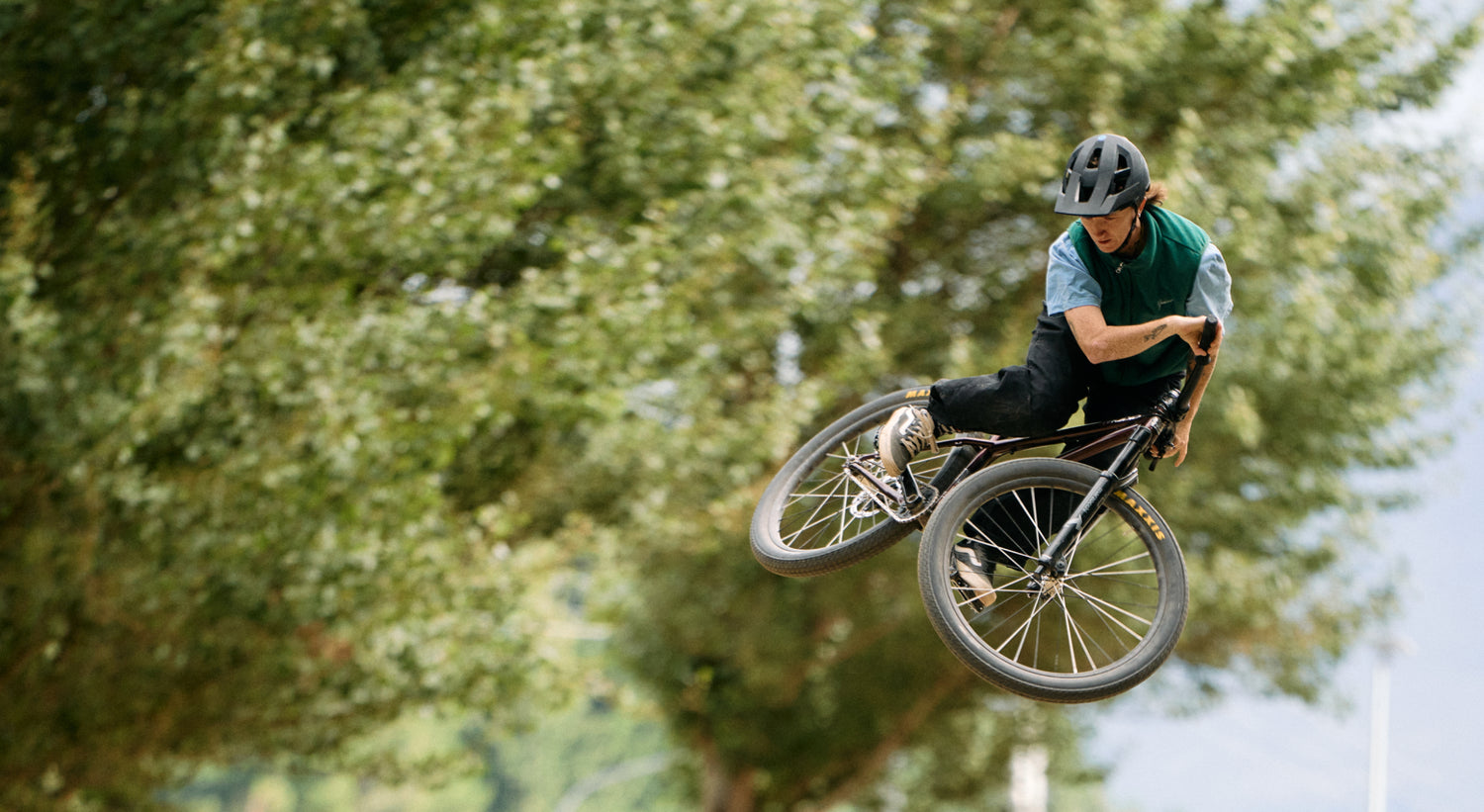 Person performing a bike trick in the air with trees in the background